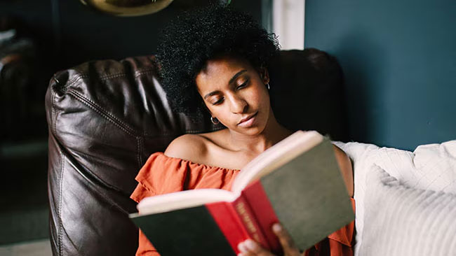 Woman sitting in a comfy chair while reading.