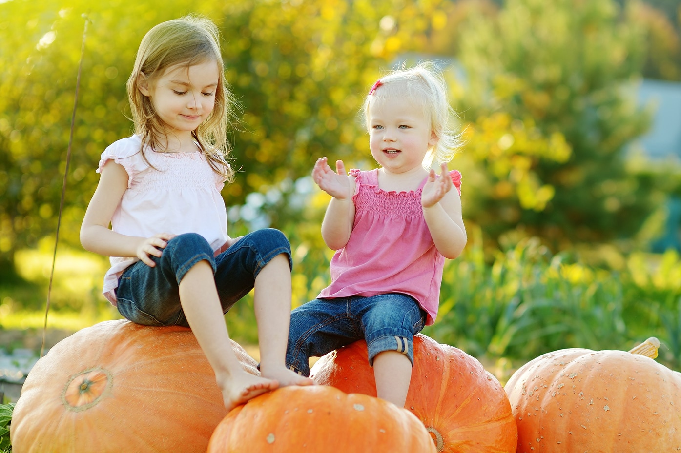 2 kids sitting on giant pumpkins