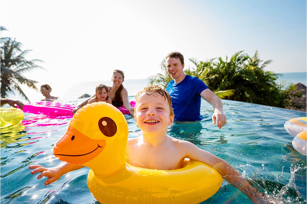 Child swimming in pool with family