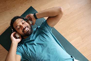 Person lying on mat and listening to headphones