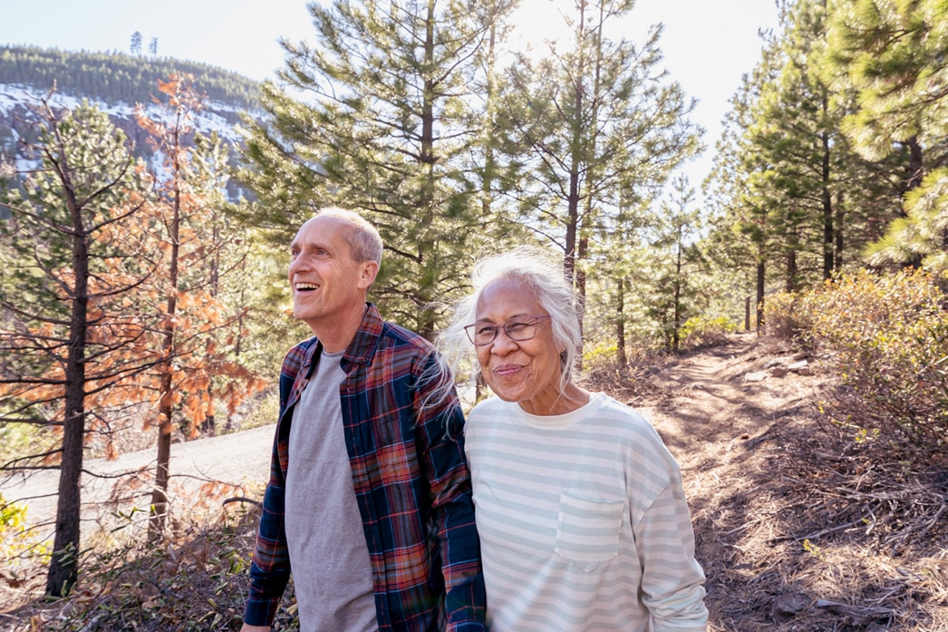 Two smiling older people walking up a trail