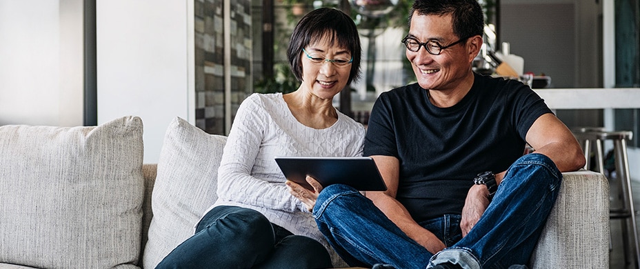 Older couple on couch looking at a tablet