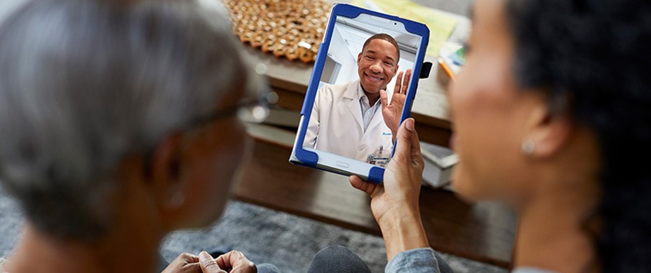 Two women look at a doctor on a tablet Two women look at a doctor on a tablet