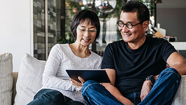 Older couple on couch looking at a tablet