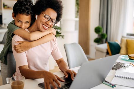 Person using laptop and hugging child