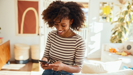 Smiling person using phone at home