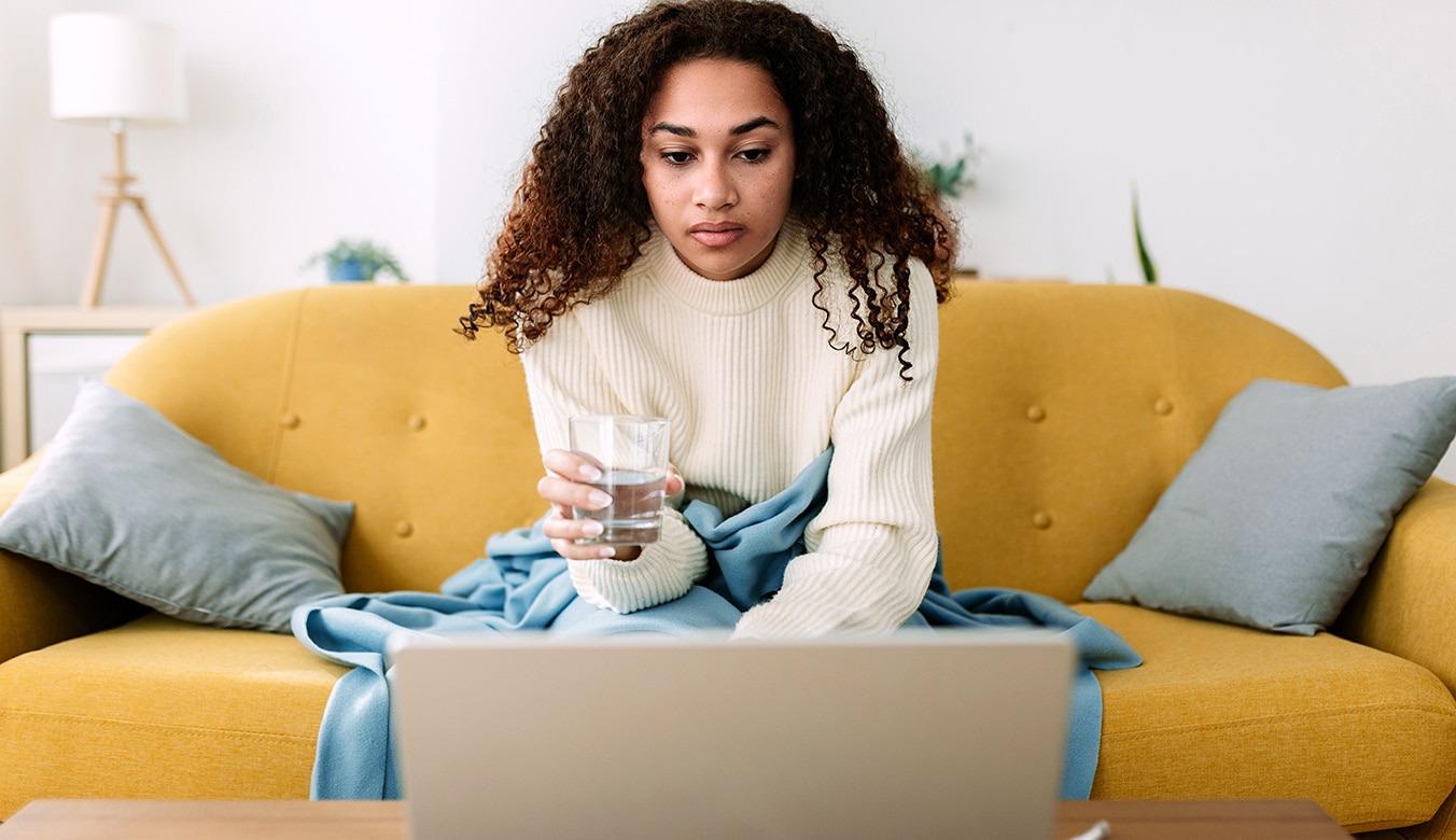 Member sitting on couch looking at laptop