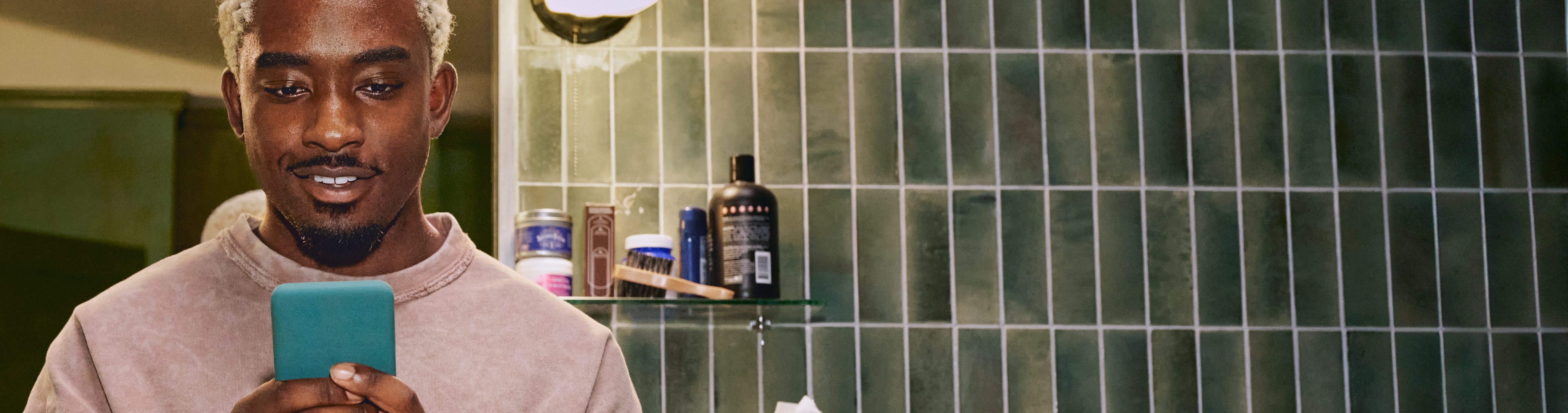 Member smiling at phone in bathroom