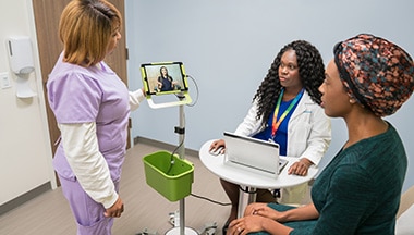 Patient, doctor, and nurse talking to specialist on video