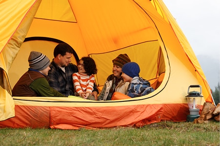 Family sitting inside a big camping tent