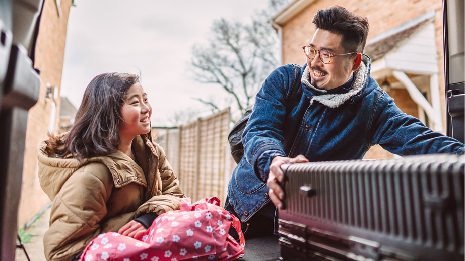 Parent and child loading luggage into car