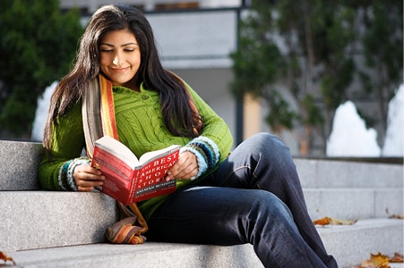  Student sitting on steps reading a book