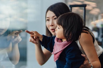 Parent pointing outside a window with their toddler