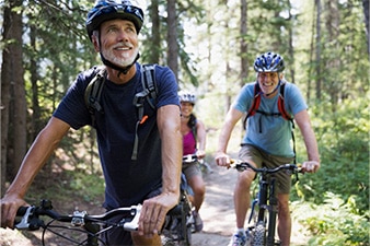 Three friends riding bikes on forest path