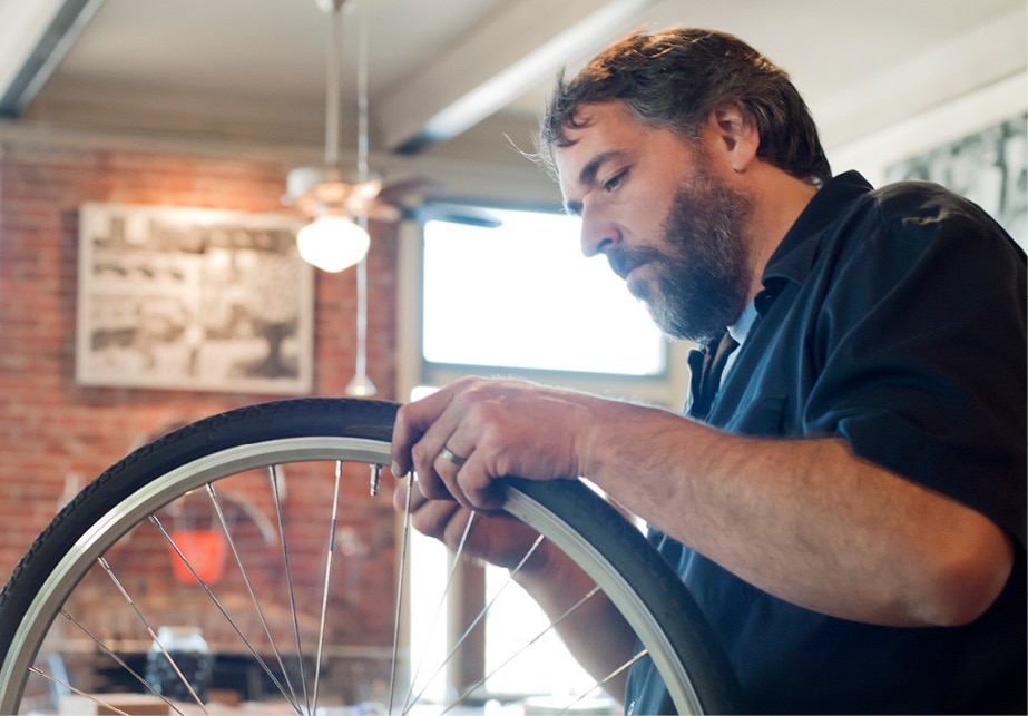 Bearded person repairing a bike tire