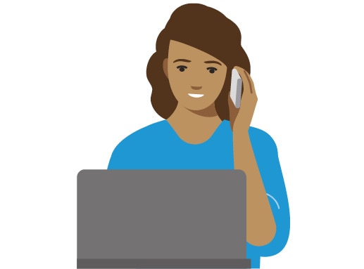 Person in a blue shirt talking on the phone in front of a laptop