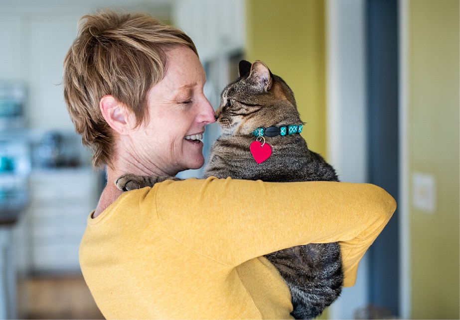 Short-haired person in a yellow shirt holding a cat