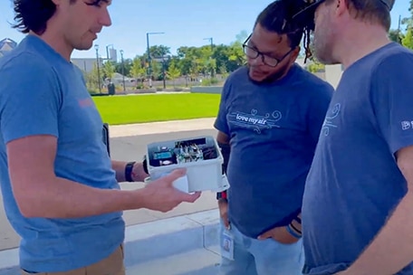 Three City of Denver Love My Air campaign workers look at an air quality monitor. 