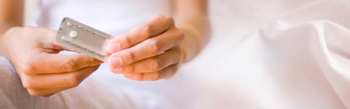 A woman's hand opening a blister pack with a white pill in it