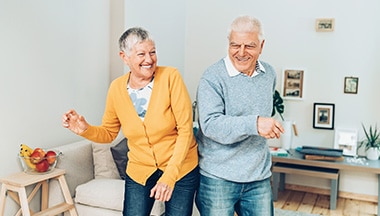 2 seniors dance in living room