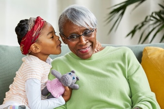 Child whispering in grandparent’s ear