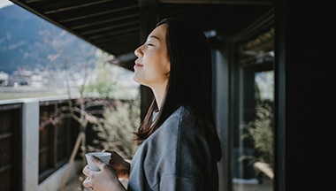 Person holding mug smiles with eyes closed