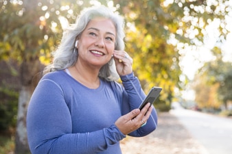 Person outdoors putting in earphones while holding a smartphone before exercising