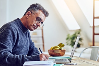 Person sitting in front of a laptop and writing