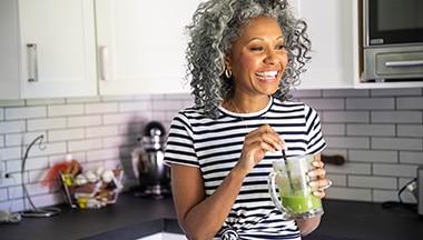 Smiling person drinking juice in kitchen