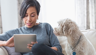 Woman using her tablet while her dog sits beside her