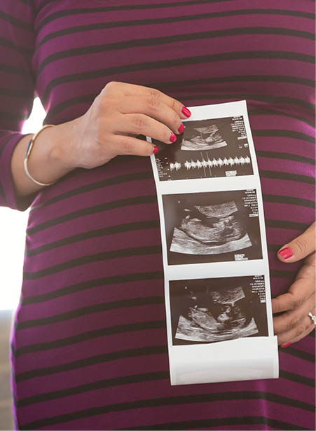 Expecting parent holding up ultrasound photos