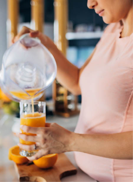 Pregnant person making fresh-squeezed orange juice