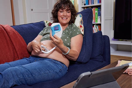 Pregnant person using a fetal heart monitor during a prenatal video visit