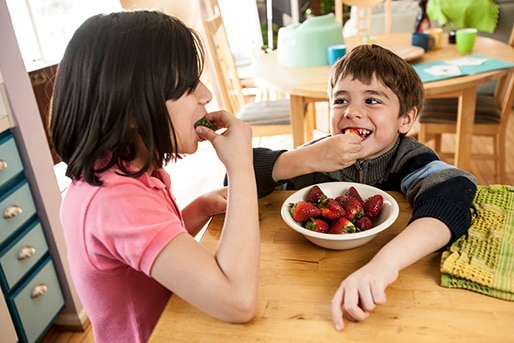 Two children eating strawberries