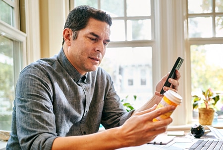 Person holding prescription bottle and mobile phone