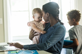 Parent holding their baby while working from home