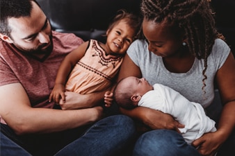 Parents holding their toddler and newborn baby