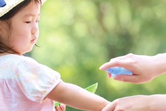 Adult applying sunscreen on the arm of a child