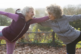 Smiling adults in workout clothes stretch outside