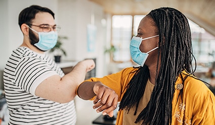 Two-co-workers-wearing-masks-and-bumping-elbows-l-dt.jpg
