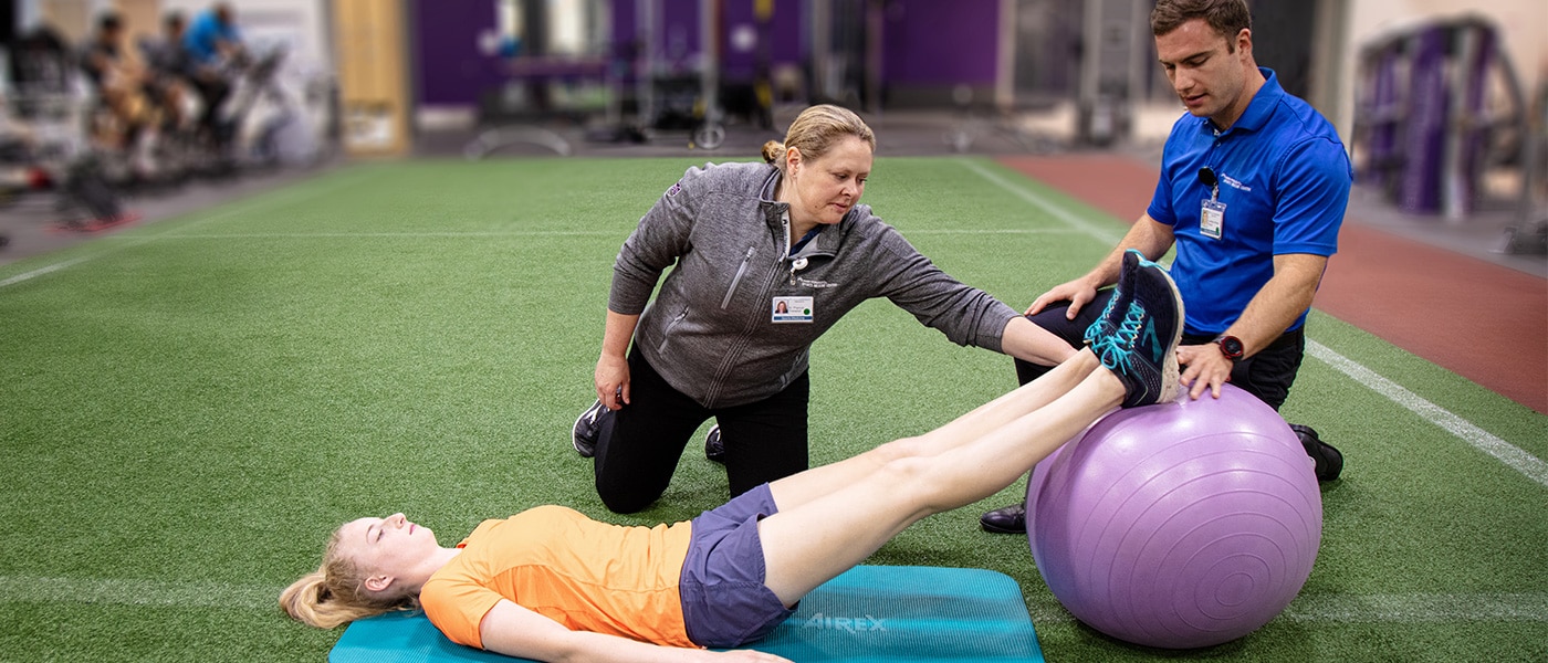 Adult doing guided floor exercise with medicine ball