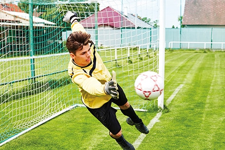 Goalie jumping to stop a soccer ball