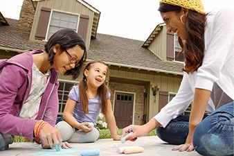 Adult and two children drawing with chalk on a sidewalk