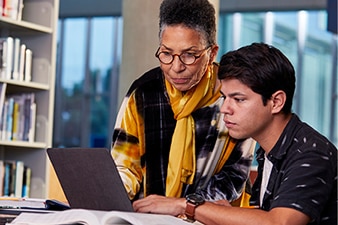 Adult helping teen on laptop