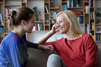 Adult talking with teen on a couch