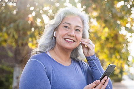 Person smiling and listening to ear buds outside