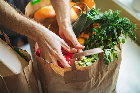 A person removing produce from a grocery bag