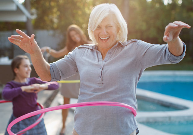 Photo of woman and children hula-hooping by pool