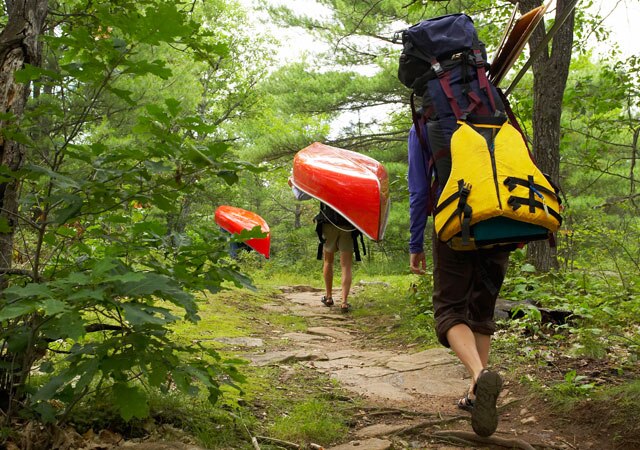 Photo of hikers carrying canoe through forest Photo of hikers carrying canoe through forest