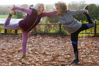 2 friends stretching together outside 